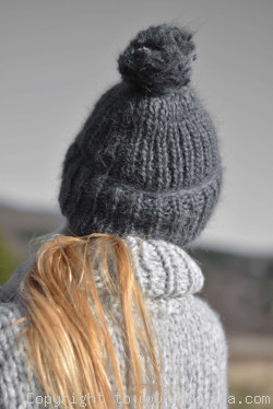 Thick winter ski hat with pompon knitted in steel gray